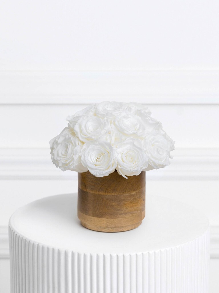Preserved white roses arranged in a soft, rounded cluster and set in a smooth wooden vase, with crisp petals and a minimalist color palette that offers timeless elegance and year-long beauty.